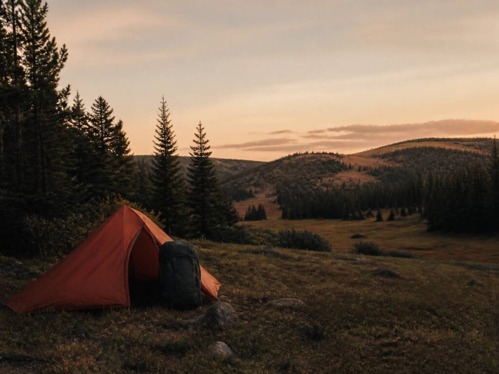 Tente de bivouac posée discrètement dans une clairière en fin de journée