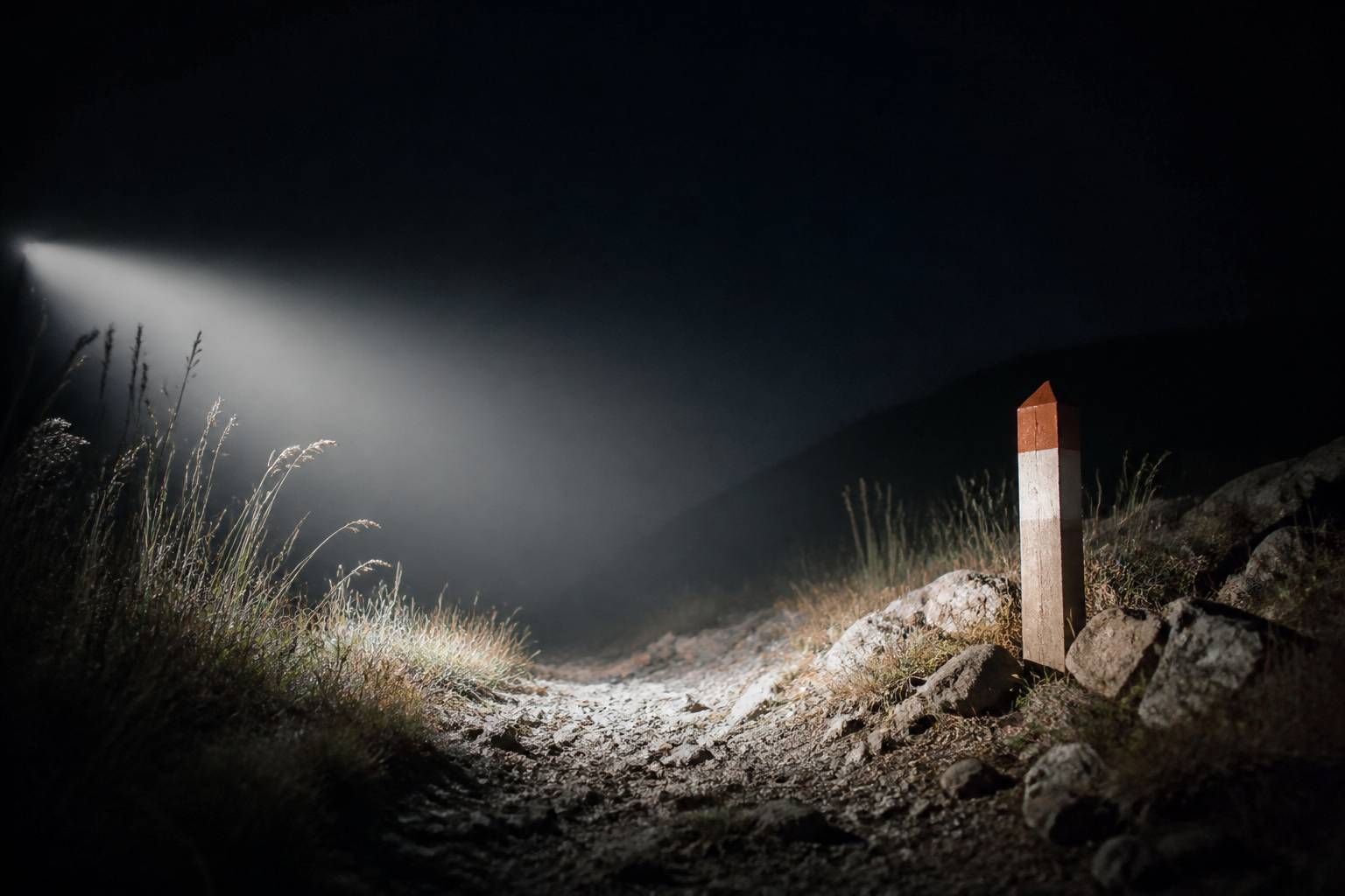 Faisceau lumineux de lampe frontale éclairant un sentier balisé la nuit