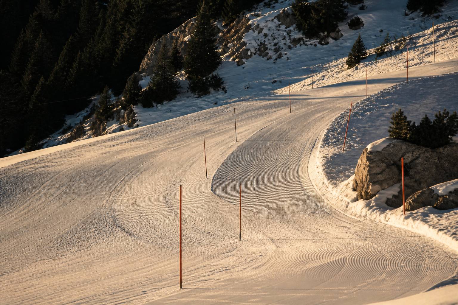 Détail d'une piste damée avec une courbe marquée et des piquets de slalom