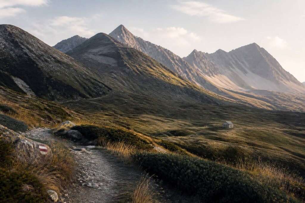 Vallée alpine des Hautes-Alpes avec un sentier de randonnée et un refuge en pierre
